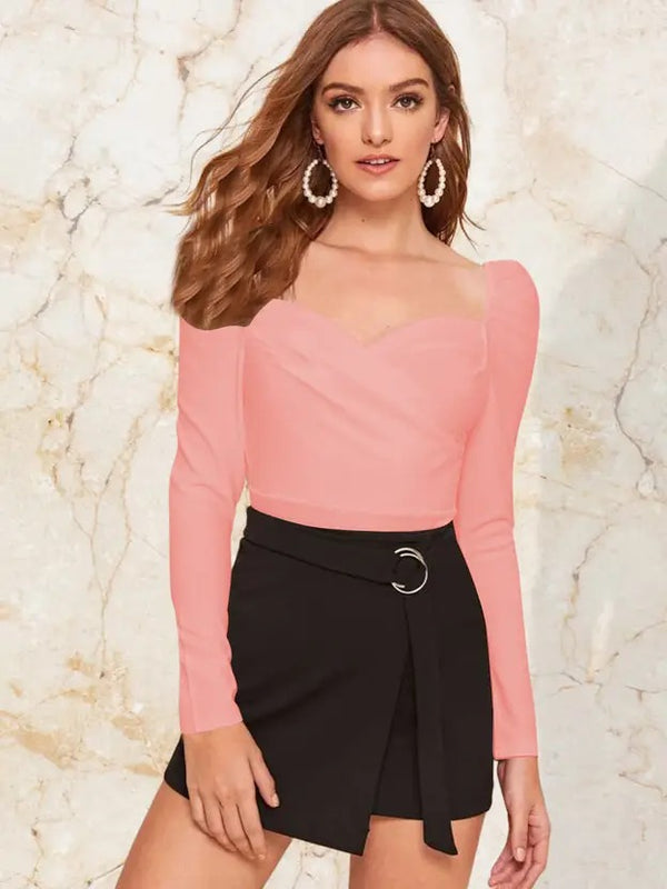 Woman wearing a pink long-sleeve top and black skirt against a marble background