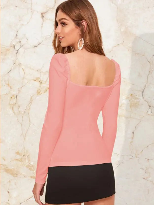 Woman wearing a pink long-sleeve top with cut-out design on a marble background